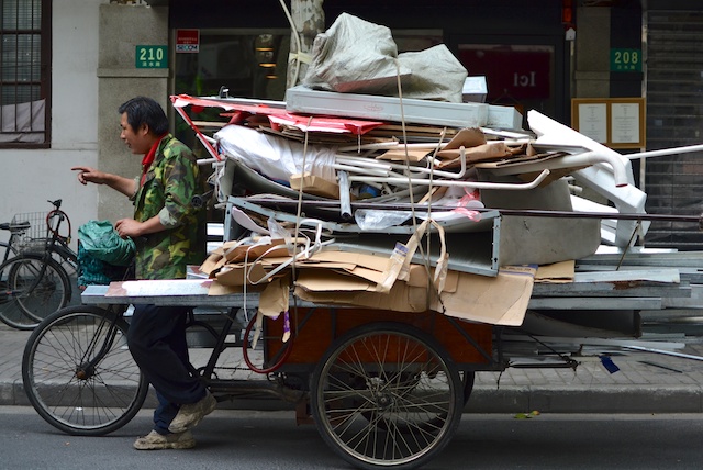 Chinese waste collector uses bicycle-pulled cart to aid his efforts in informal recycling.